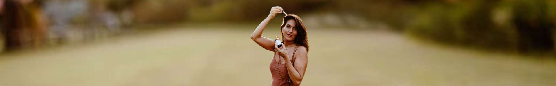 Woman applying Osi Oils Radiance Ayurvedic Hair & Scalp Oil to her scalp promoting healthy and shiny hair