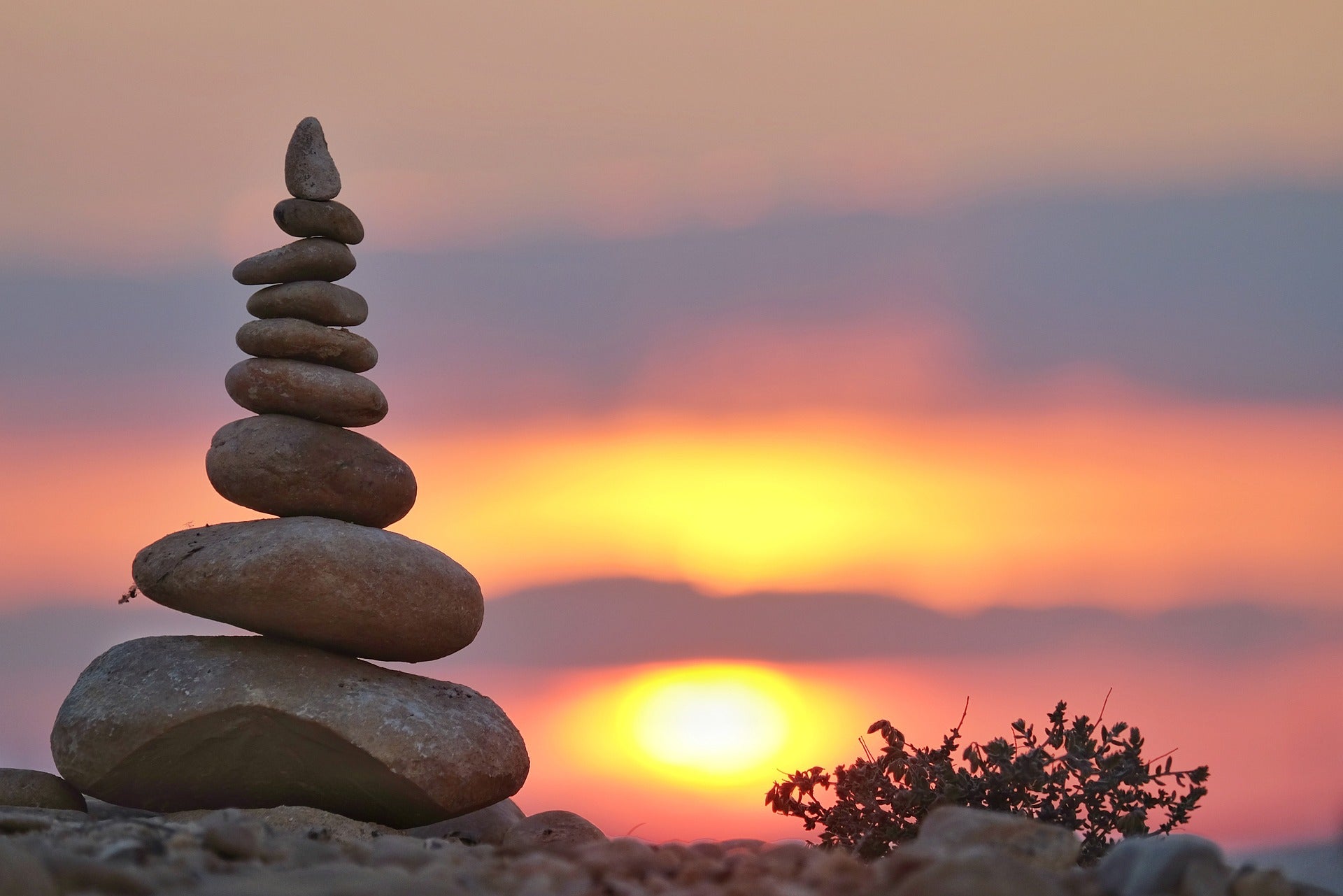 Stacked stones balanced at sunset symbolizing spiritual reflection and emotional grounding