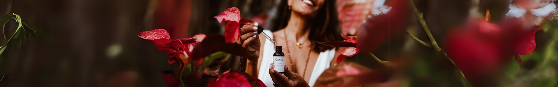 Woman holding Osi Oils Glow Oil surrounded by pink leaves and flowers, embracing self-love and Ayurvedic beauty rituals