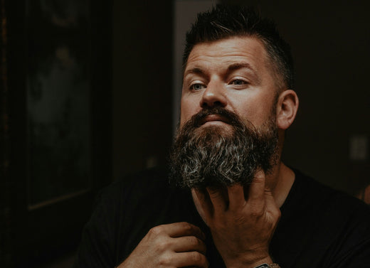 Man massaging his beard with Ayurvedic Face and Beard Balm in the mirror, promoting healthy grooming and wellness for Father’s Day